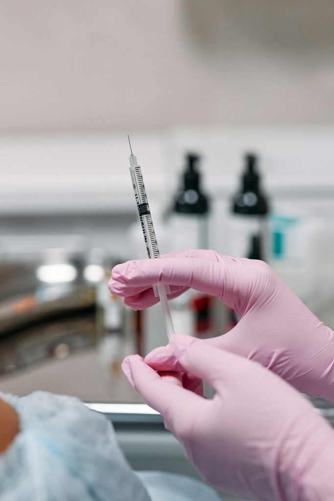 Medical professional wearing pink gloves preparing syringe for Botox injection treatment at Elect Dermatology in New Braunfels TX